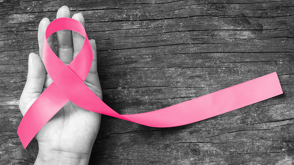 Picture of  a hand holding a pink breast cancer awareness ribbon